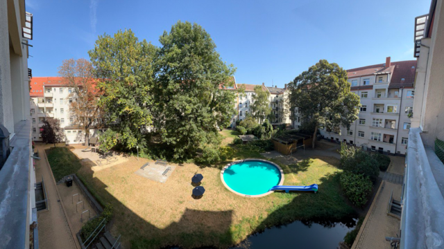 großer Innenhof mit großen Bäumen, blauem Pool sowie ein Teich am unteren Bildrand